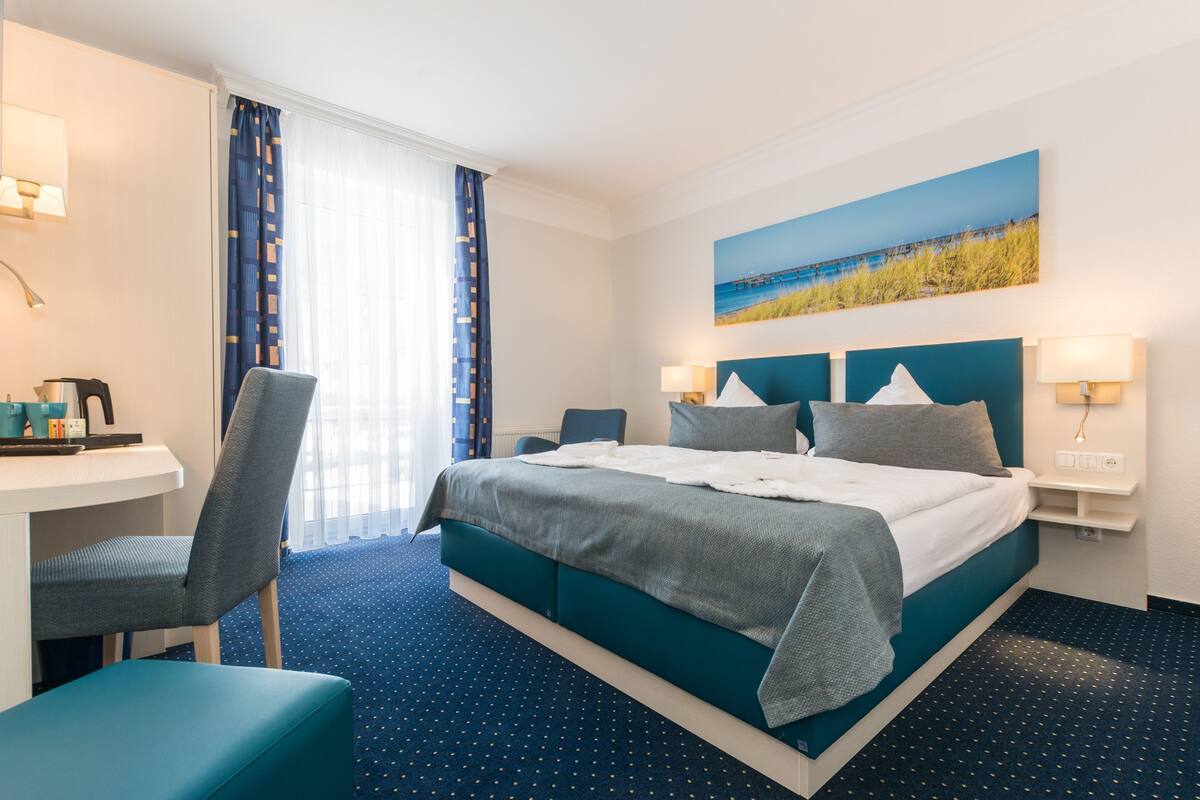 A hotel room with a bed, a desk, and a chair.