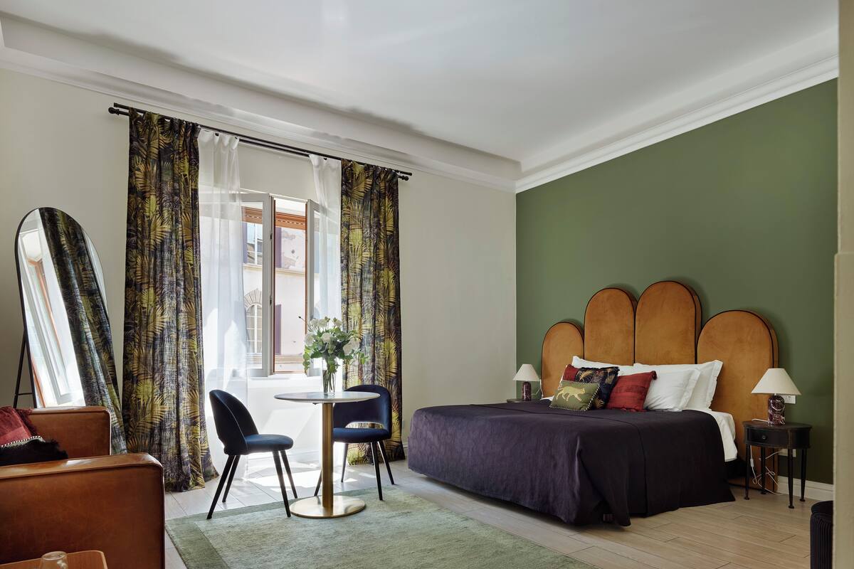 Een hotelkamer met een bed, een bureau, een stoel, een spiegel en uitzicht.