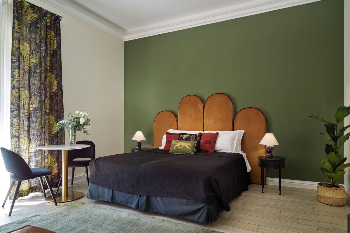 Een keurig opgemaakt slaapkamer met een groot bed, een klein rond tafeltje en een stoel.
