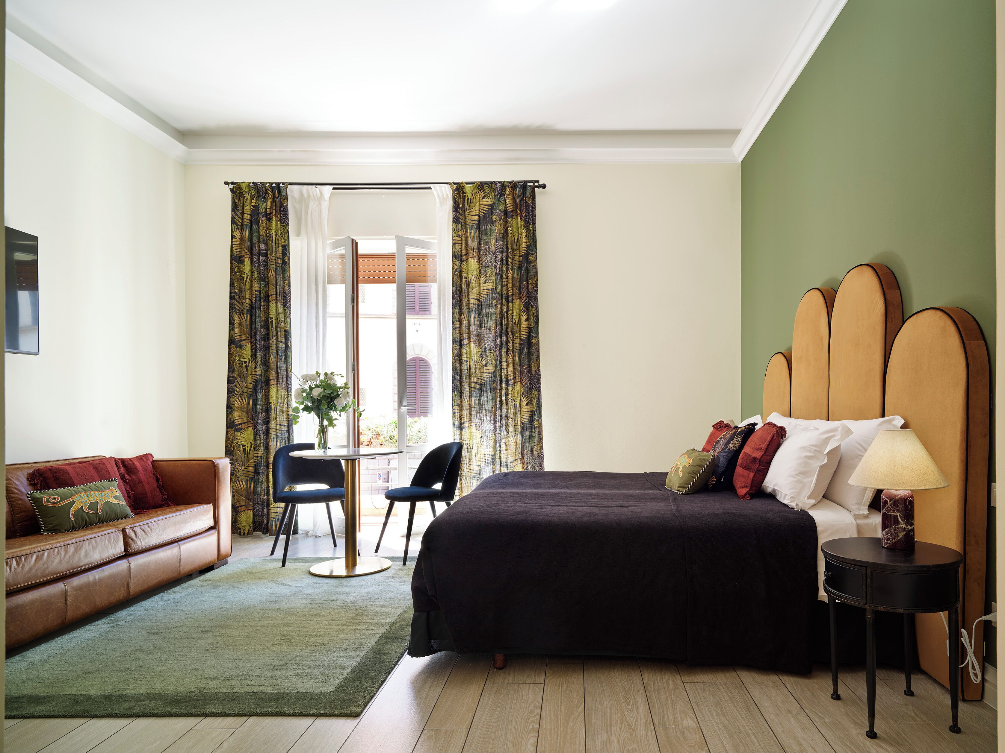 A bedroom with a bed, a sofa, a small table, and chairs.
