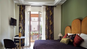 Une chambre d’hôtel équipée d’un lit, d’un bureau, d’une chaise, d’une télévision et offrant une vue sur l’extérieur.
