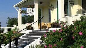 A porch with a 'WELCOME' sign, steps, and potted plants.