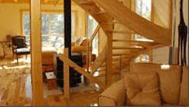 A rustic wooden interior with exposed beams, a staircase, and a cozy seating area.