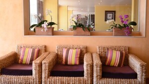 Trois chaises en osier avec des coussins à rayures et des orchidées en pot, le tout placé devant un mur jaune.