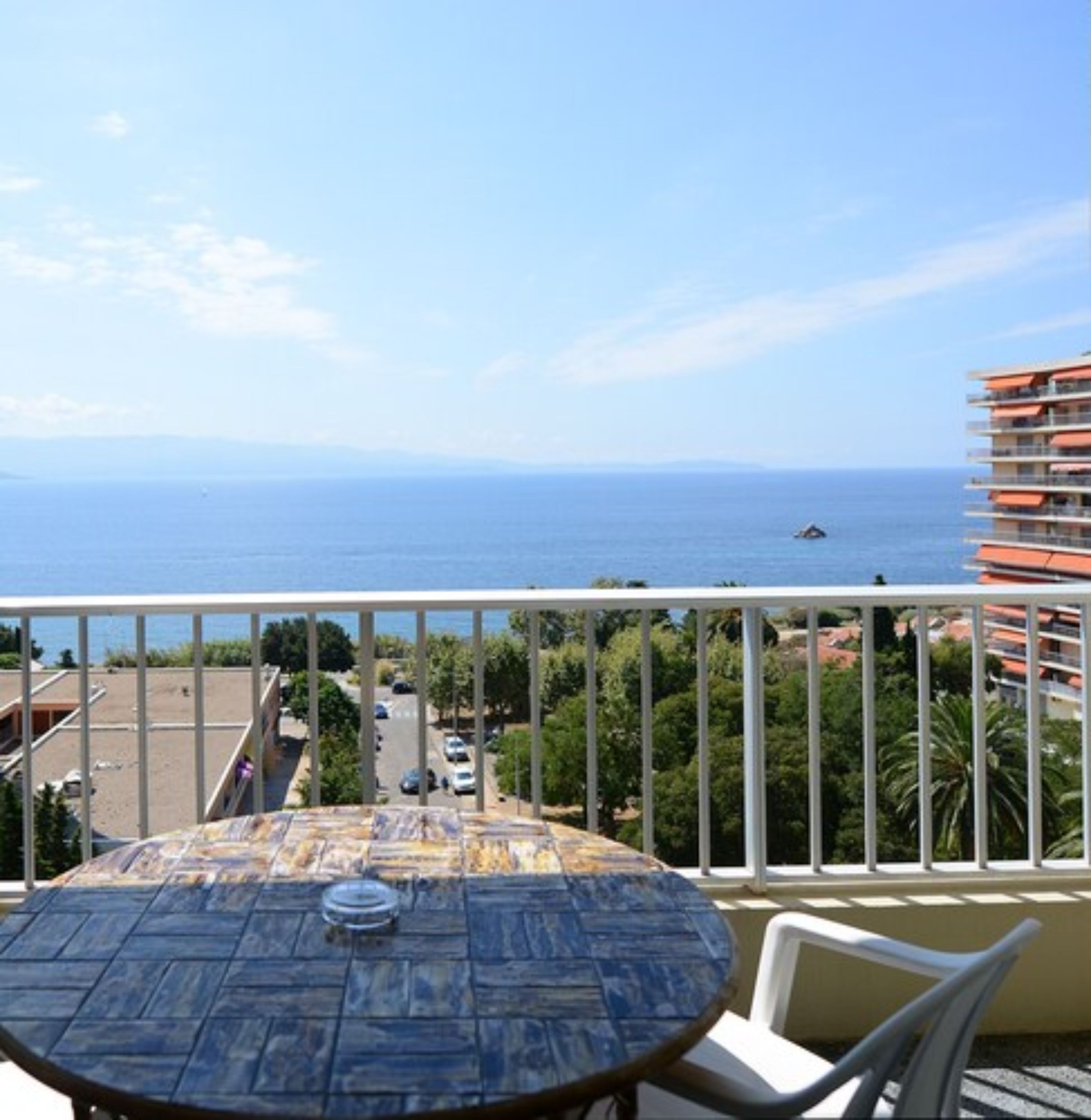 A balcony with a table and chairs overlooking a coastal view.