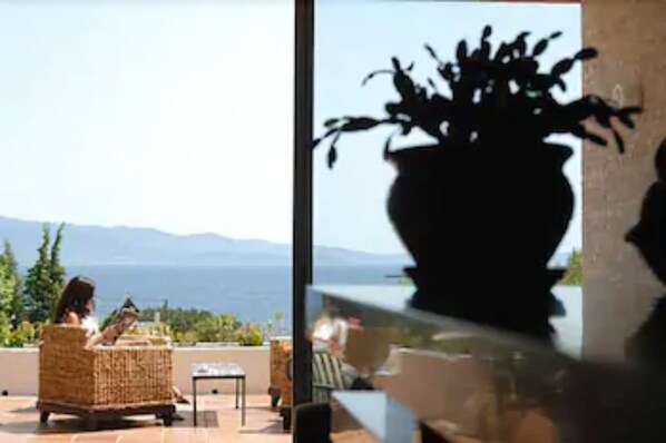 A room with a view of the sea and mountains, a wicker chair, and a potted plant. - Sun Beach Hôtel (Ajaccio)