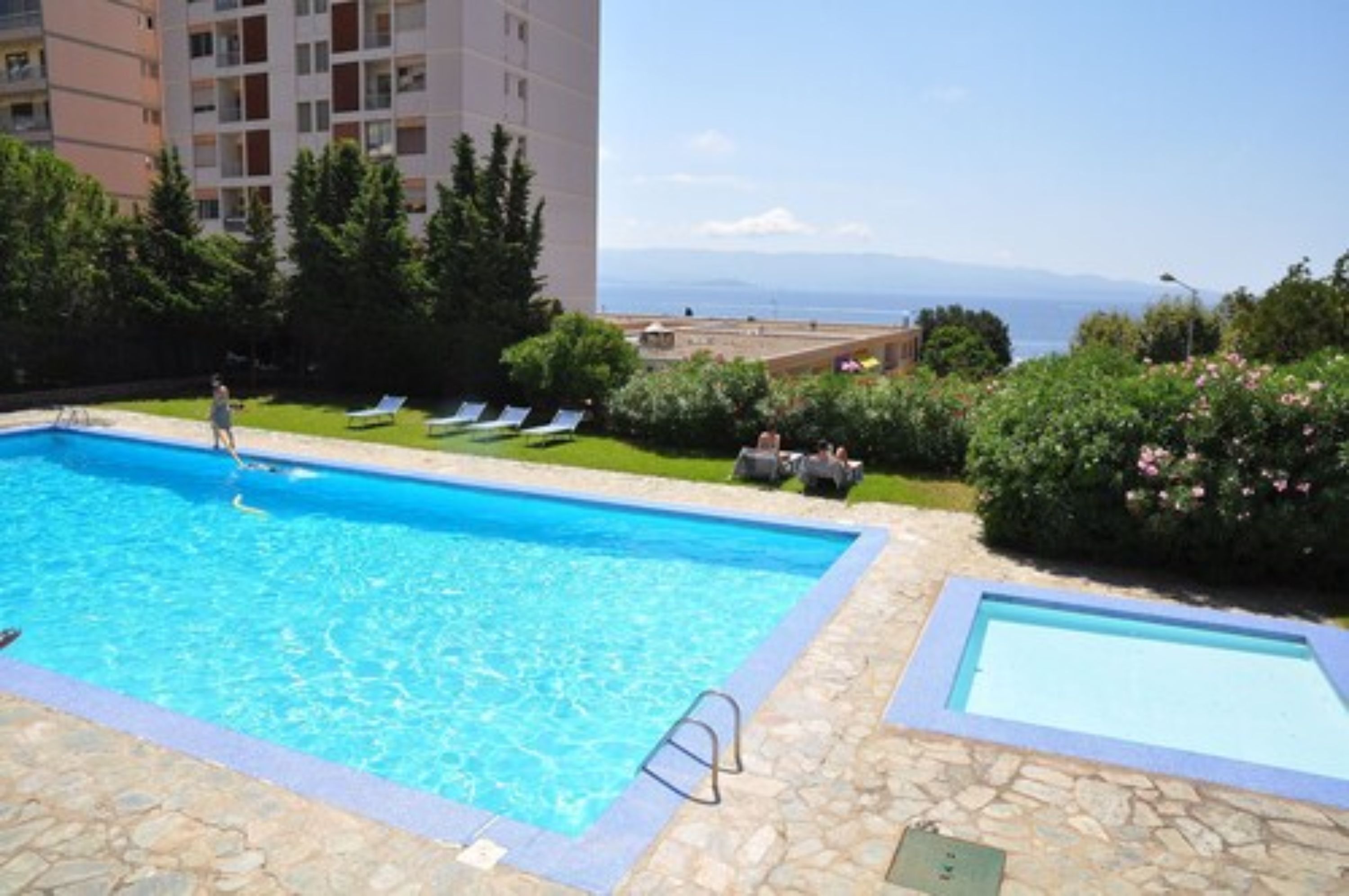 Une piscine offrant une vue dégagée sur la mer et les montagnes en arrière-plan.
