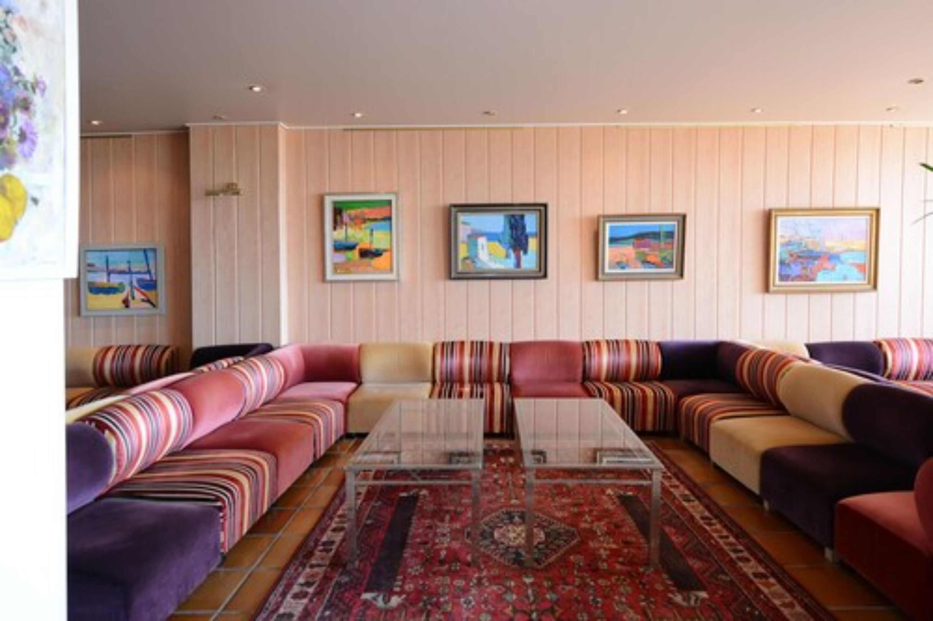 Un salon moderne avec un canapé d’angle, une table basse en verre et un tapis à motifs.