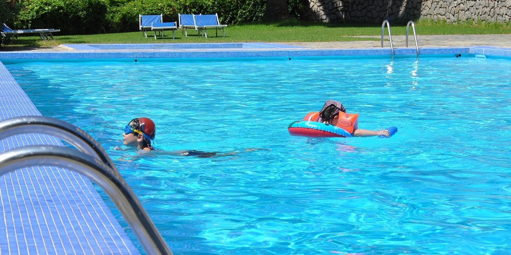 Une piscine à l’eau d’un bleu cristallin, un plongeoir et, au fond, des chaises longues.