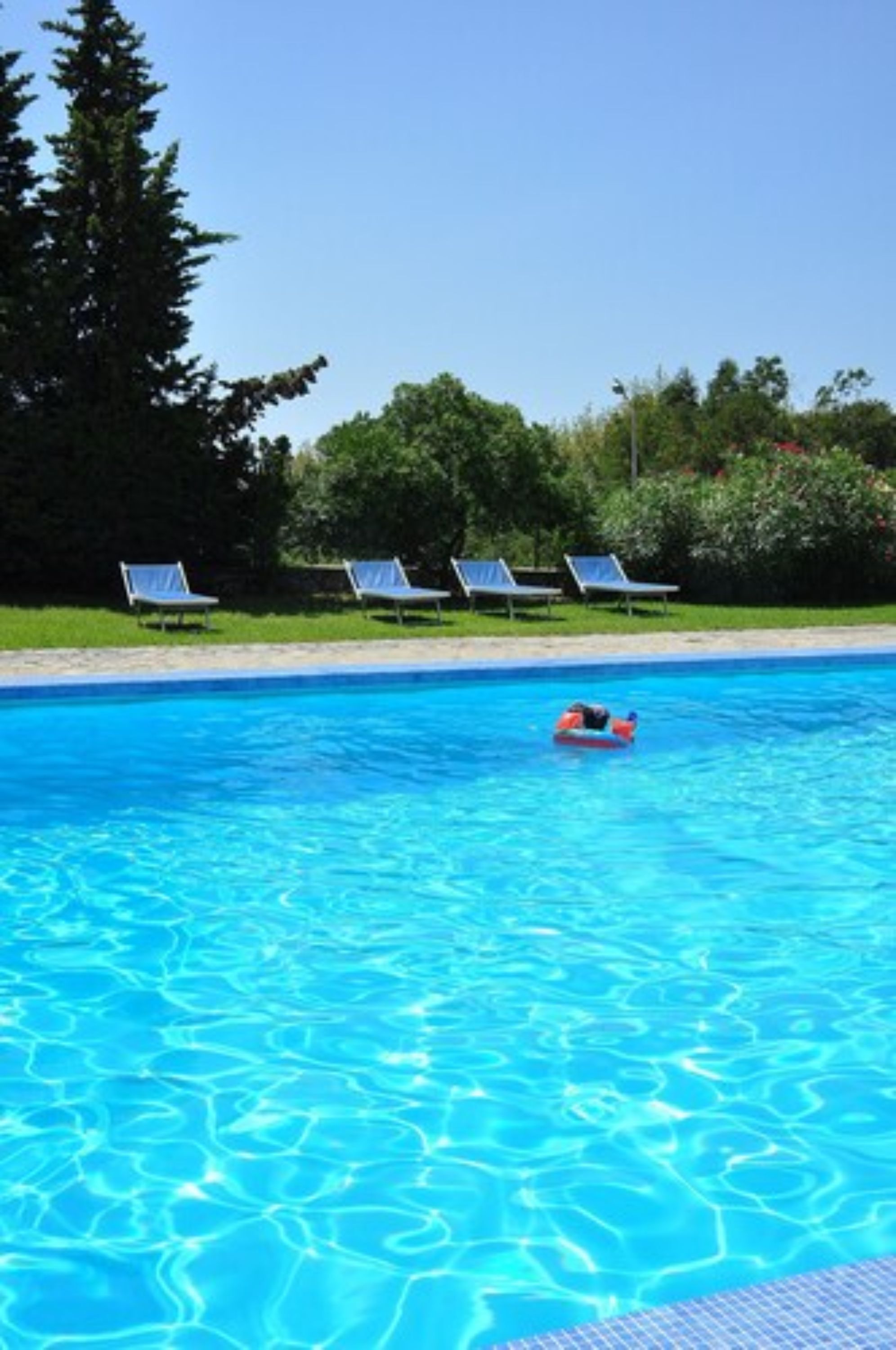Una piscina al aire libre, sillones reclinables de piscina
