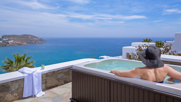 A person relaxing in a hot tub with a view of the sea and a mountainous landscape. - Pietra e Mare - Mykonos Moments by Mr and Mrs White (Mykonos)