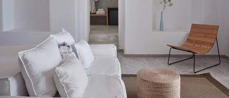 A modern interior with a white sofa, a wooden chair, and a wicker ottoman.