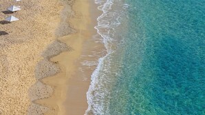 An aerial view of a beach with clear turquoise water and a sandy shore. - Pietra e Mare - Mykonos Moments by Mr and Mrs White (Mykonos)