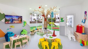 A children's playroom with a play area, a table with chairs, and a mural on the wall. - HD Parque Cristobal Tenerife (Arona)