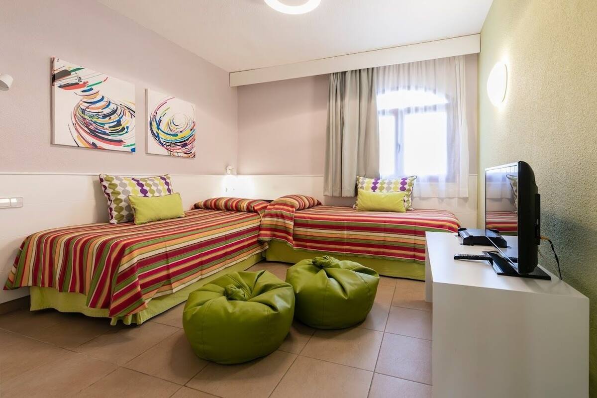 Une chambre d’hôtel avec deux lits, une télévision et des œuvres d’art accrochées au mur.
