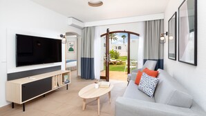 A modern living room with a flat-screen TV, a sofa, a coffee table, and a view of an outdoor patio. - HD Parque Cristobal Tenerife (Arona)