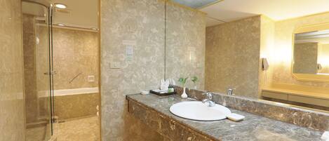 A modern bathroom with a glass-enclosed shower, a marble vanity, and a large mirror.