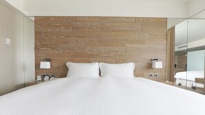 Quarto de hotel moderno com uma cama grande, cabeceira de madeira, luminárias de cabeceira e um espelho.