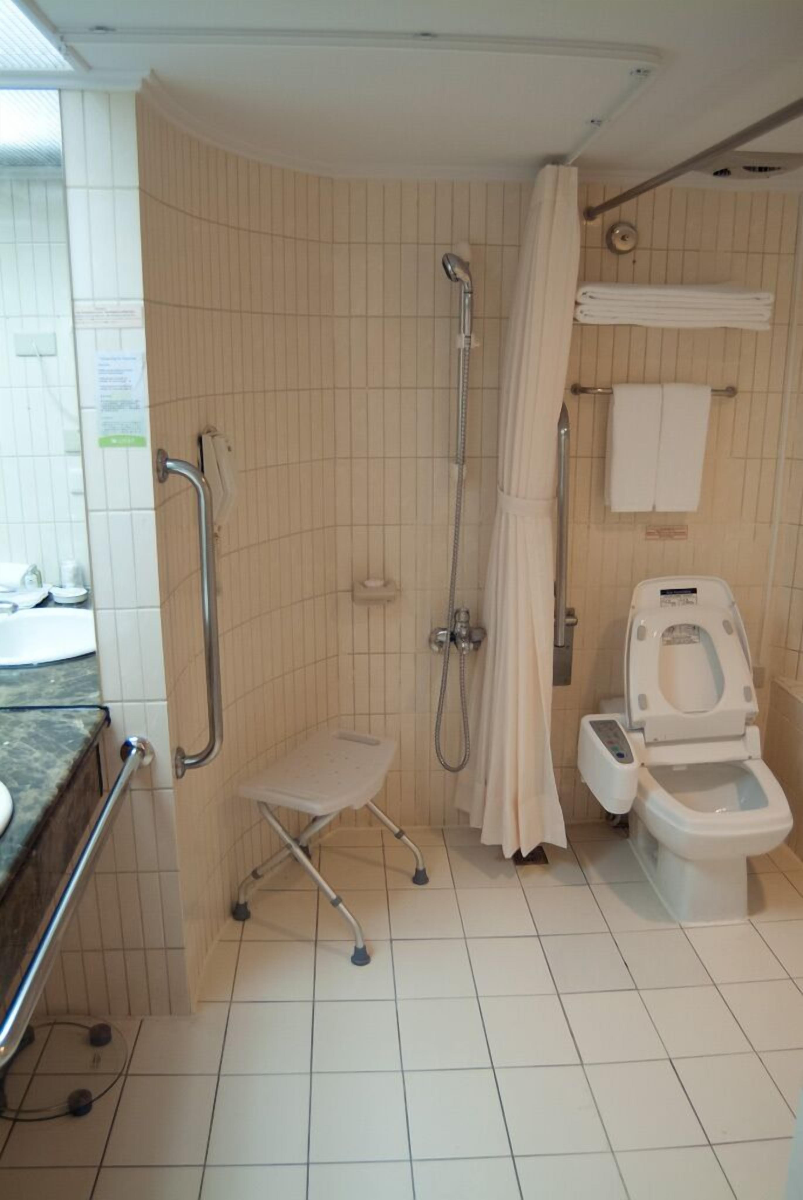A bathroom with a shower, toilet, and grab bars.