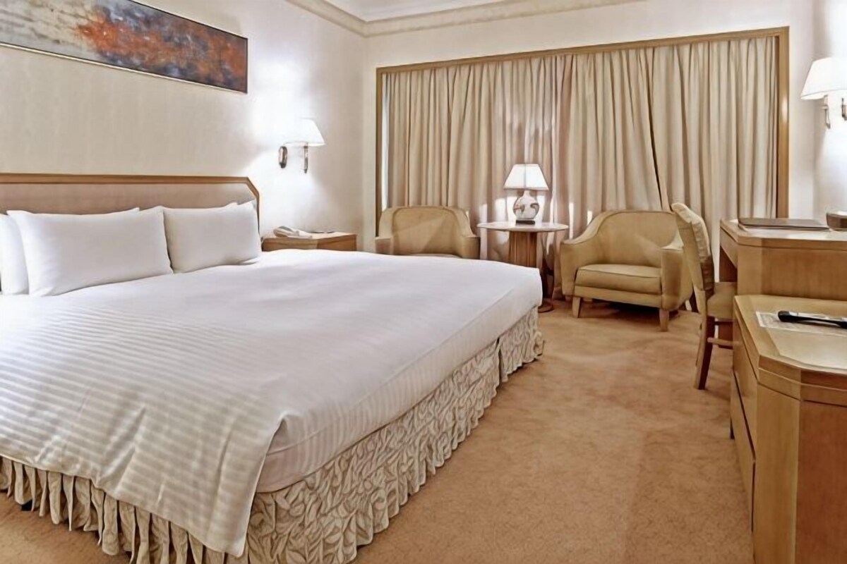 Habitación de hotel con una cama grande, un escritorio, una silla y una lámpara.
