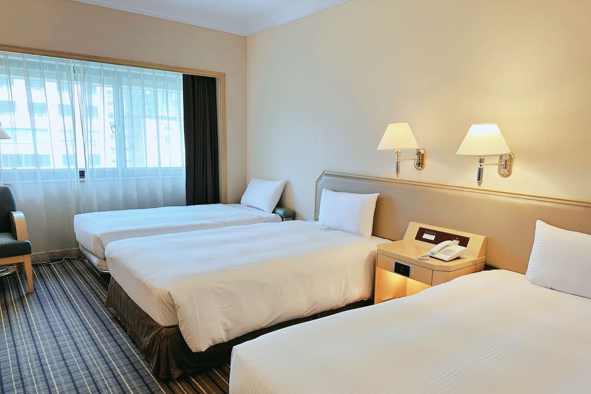 A hotel room with two beds, a desk with a telephone, and a chair.