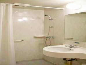 Bathroom features a shower area, sink with a single faucet, and a mirror above.
