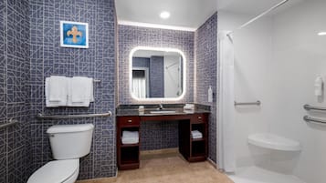Un baño moderno con inodoro, tocador con espejo y zona de ducha.