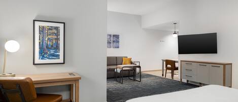A hotel room with a bed, desk, chair, and a TV on the wall.