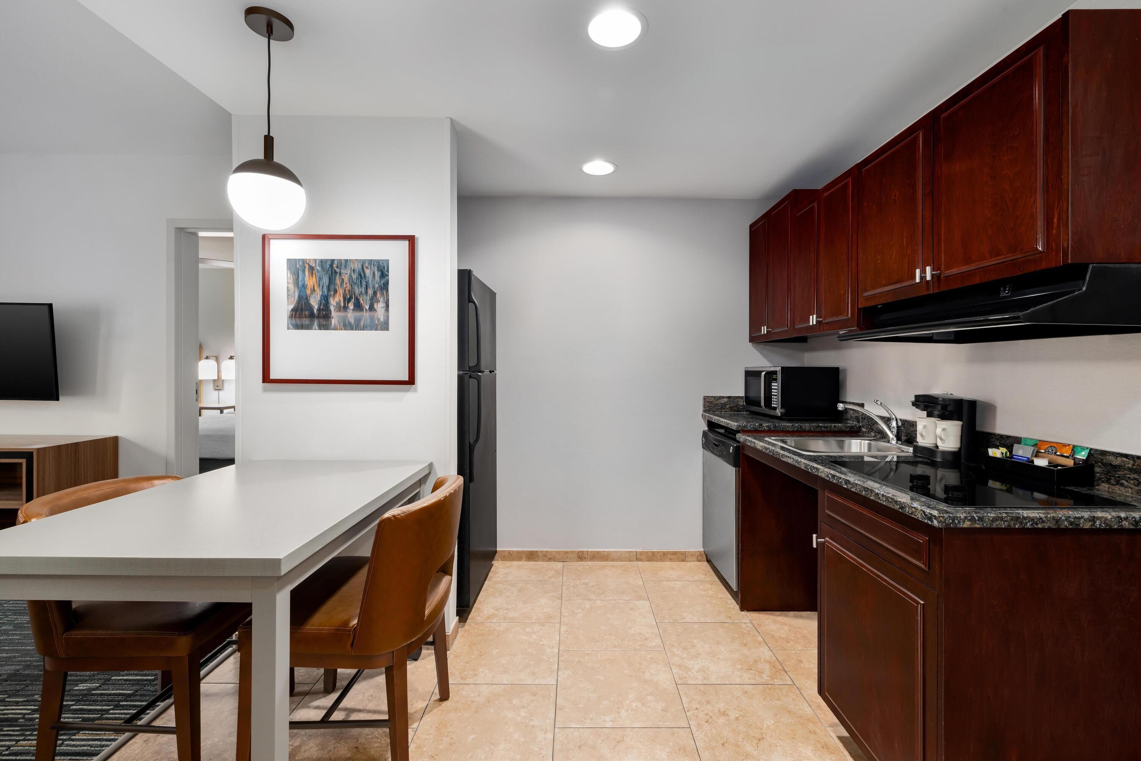 A modern kitchen with a white countertop, dark wooden cabinets, and a built-in oven.