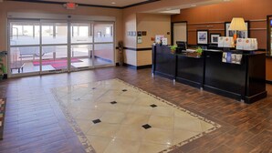 A hotel reception area with a check-in desk, a large glass door entrance, and a patterned rug on the floor. - Hampton Inn Pecos (Pecos)