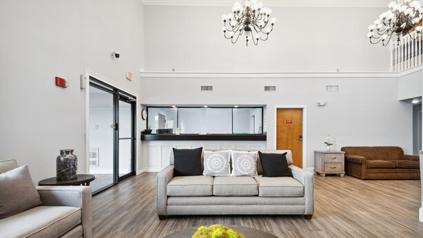 A modern living room with a grey sofa, a coffee table with a moss centerpiece, and a wooden floor. - My Hometown Inn (Mooresville)