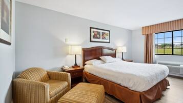 A hotel room with a large bed, two bedside tables with lamps, a sofa, and a chair.