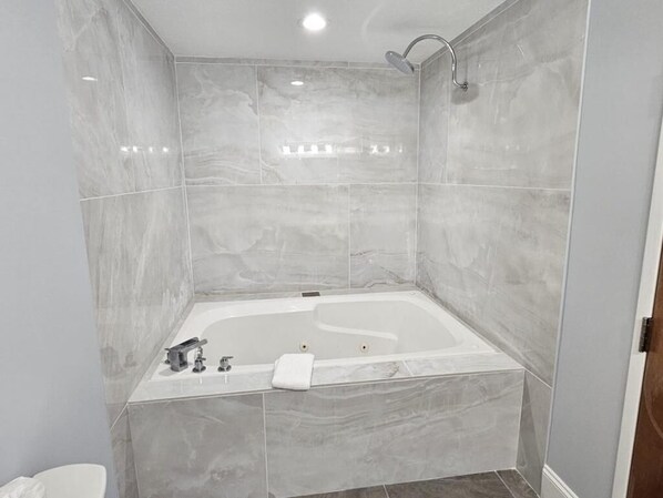 A modern bathroom with a freestanding bathtub, a showerhead, and a toilet. - My Hometown Inn (Mooresville)