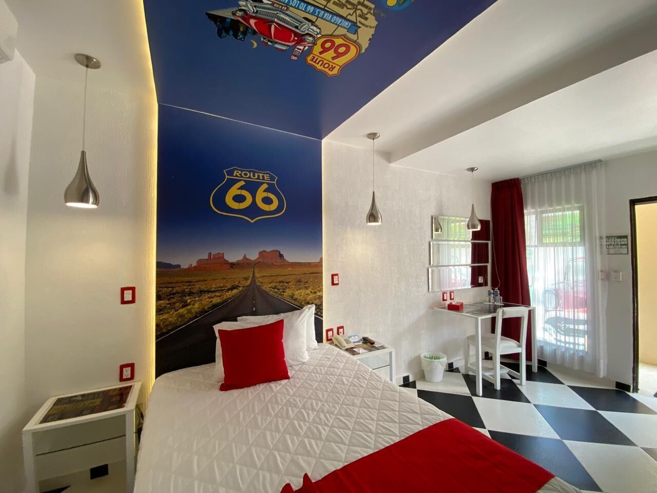 A hotel room with a large bed, a desk, and a view of the outdoors.