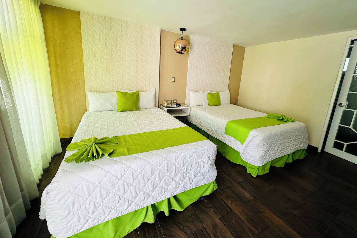Una habitación de hotel con dos camas, una mesita de noche y una puerta.