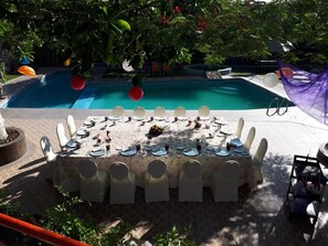 An outdoor dining area with a pool in the background.