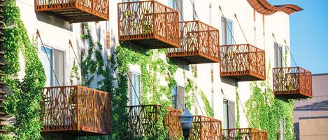 Un edificio con varios balcones con barandillas de metal intrincadas, rodeado de exuberante hiedra verde.
