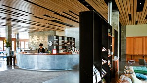 Un hall d’entrée moderne avec un comptoir d’accueil central, un espace salon agrémenté d’un canapé à motifs et une bibliothèque remplie de livres.