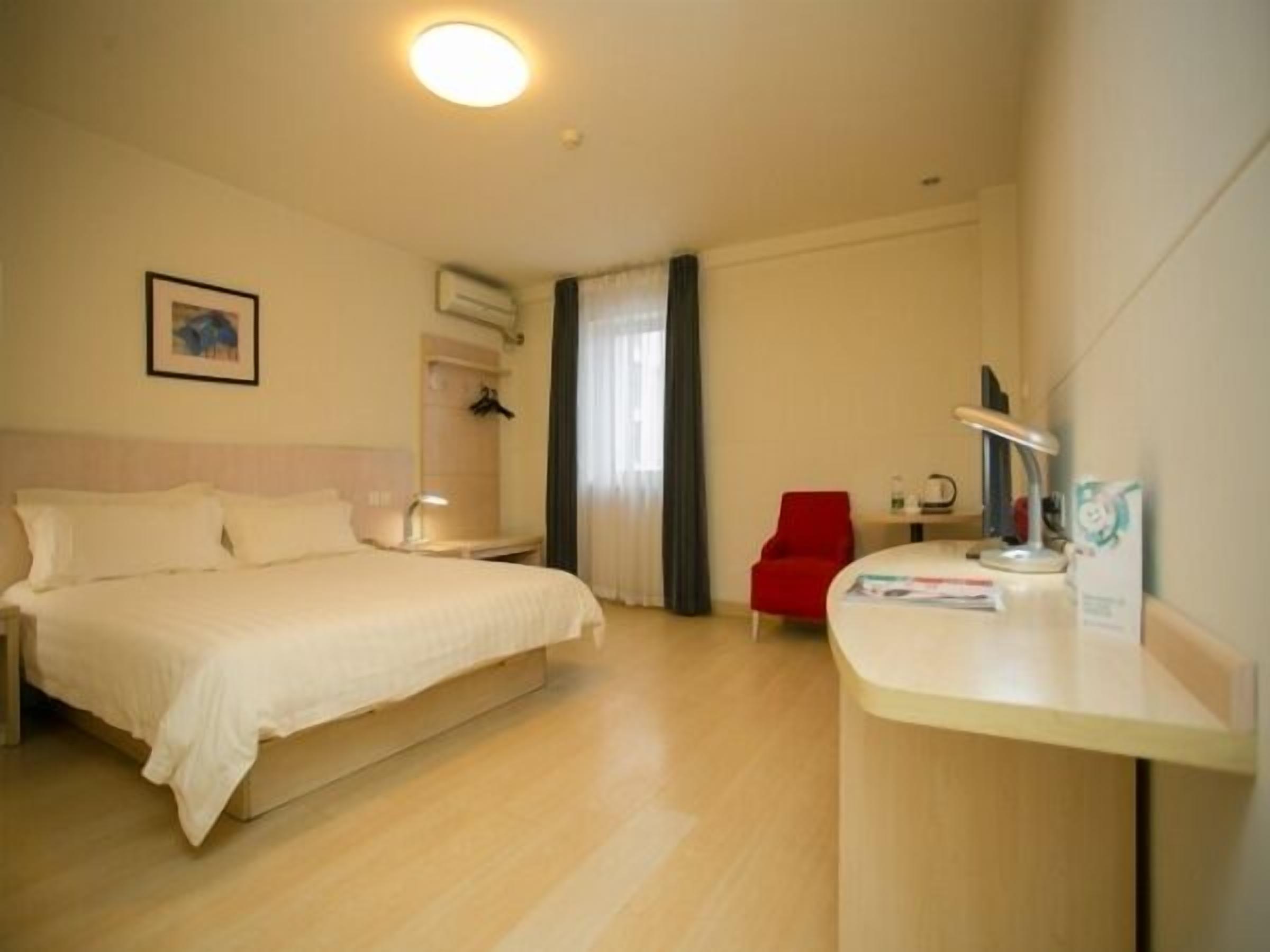 A hotel room with a bed, a desk, a chair, and a window with curtains.