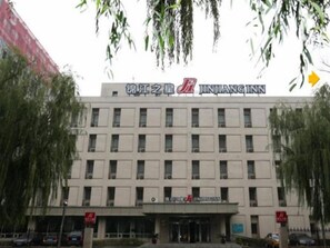 Un edificio de varios pisos con un letrero que dice 'Jinjiang Inn' en la parte superior.