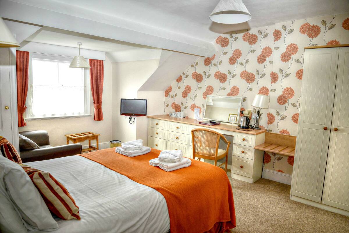 Ein Hotelzimmer mit Bett, Schreibtisch, Stuhl, Fernseher und Kleiderschrank.