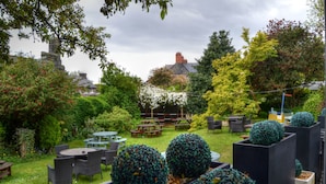 A garden with outdoor seating, a stone wall, and a variety of plants.