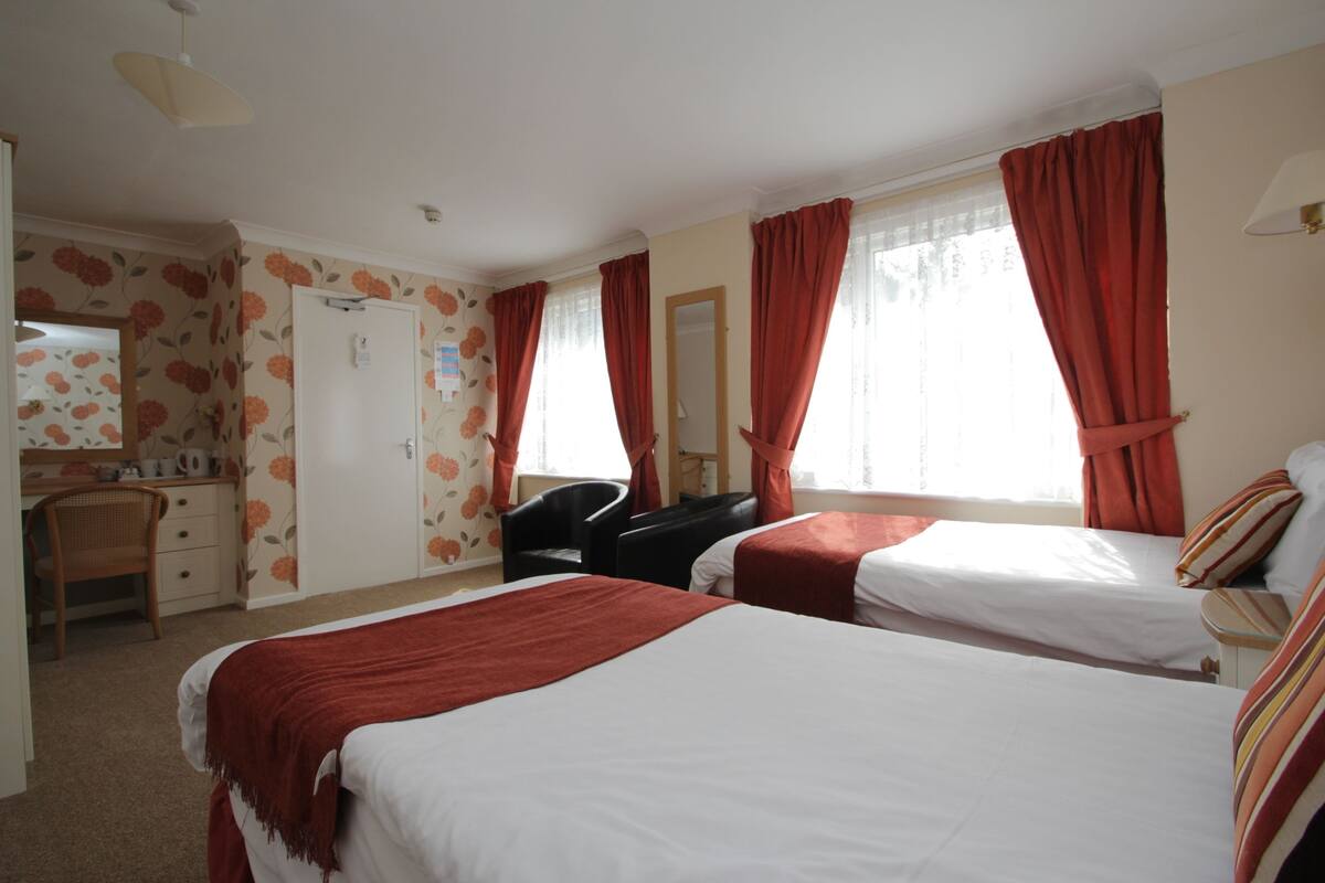 Ein Hotelzimmer mit zwei Betten, einem Schreibtisch, einem Stuhl und einem Spiegel.