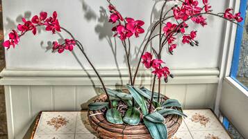 Una cesta de mimbre con orquídeas rosadas sobre un suelo de baldosas.