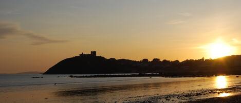 A beach with a castle silhouette against the sunset.