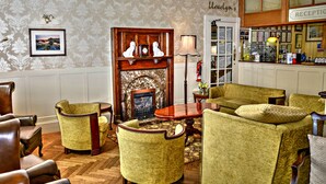 A traditional interior with a fireplace, leather armchairs, and a reception area.