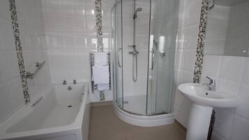 A modern bathroom with a glass-enclosed shower, a bathtub, and a sink.