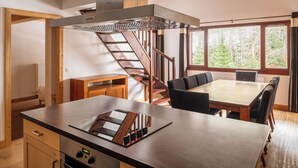 A modern kitchen with a central island, built-in stove, and a wooden staircase. - Dormio Resort Les Portes du Mont Blanc (Vallorcine)