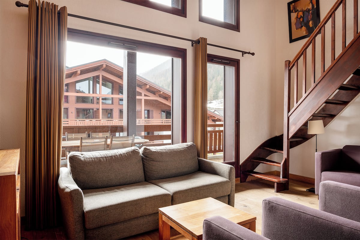 A cozy living room with a sofa, a coffee table, and a staircase.