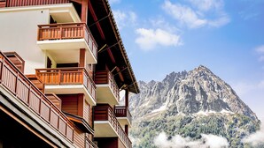 A multi-story building with balconies and a mountain backdrop. - Dormio Resort Les Portes du Mont Blanc (Vallorcine)